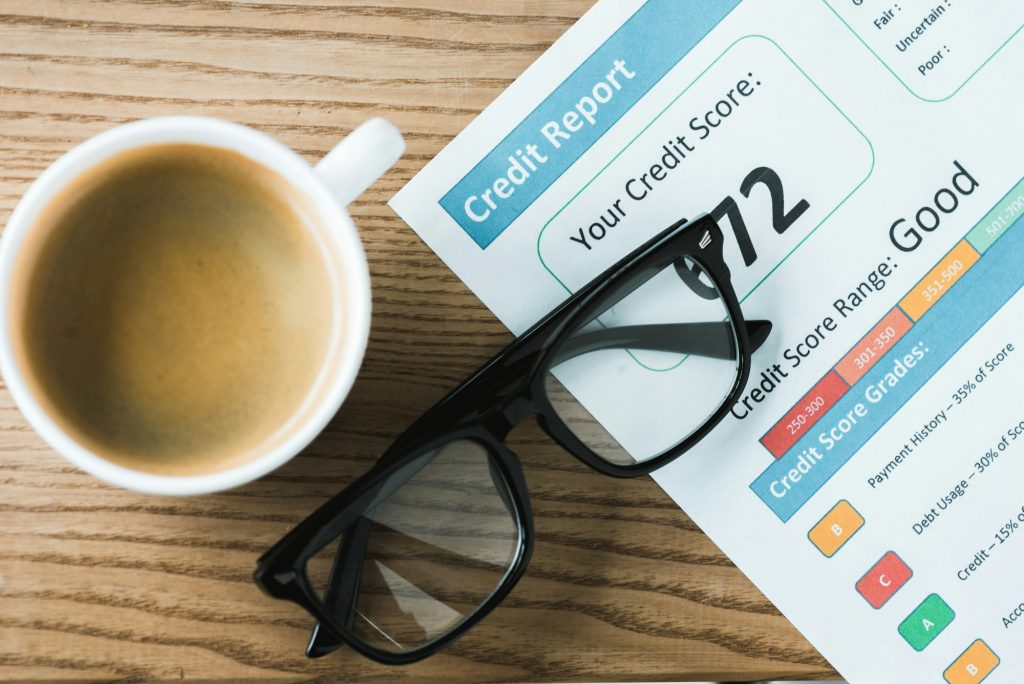 top view of cup with coffee near paper with credit report lettering on paper and glasses on table